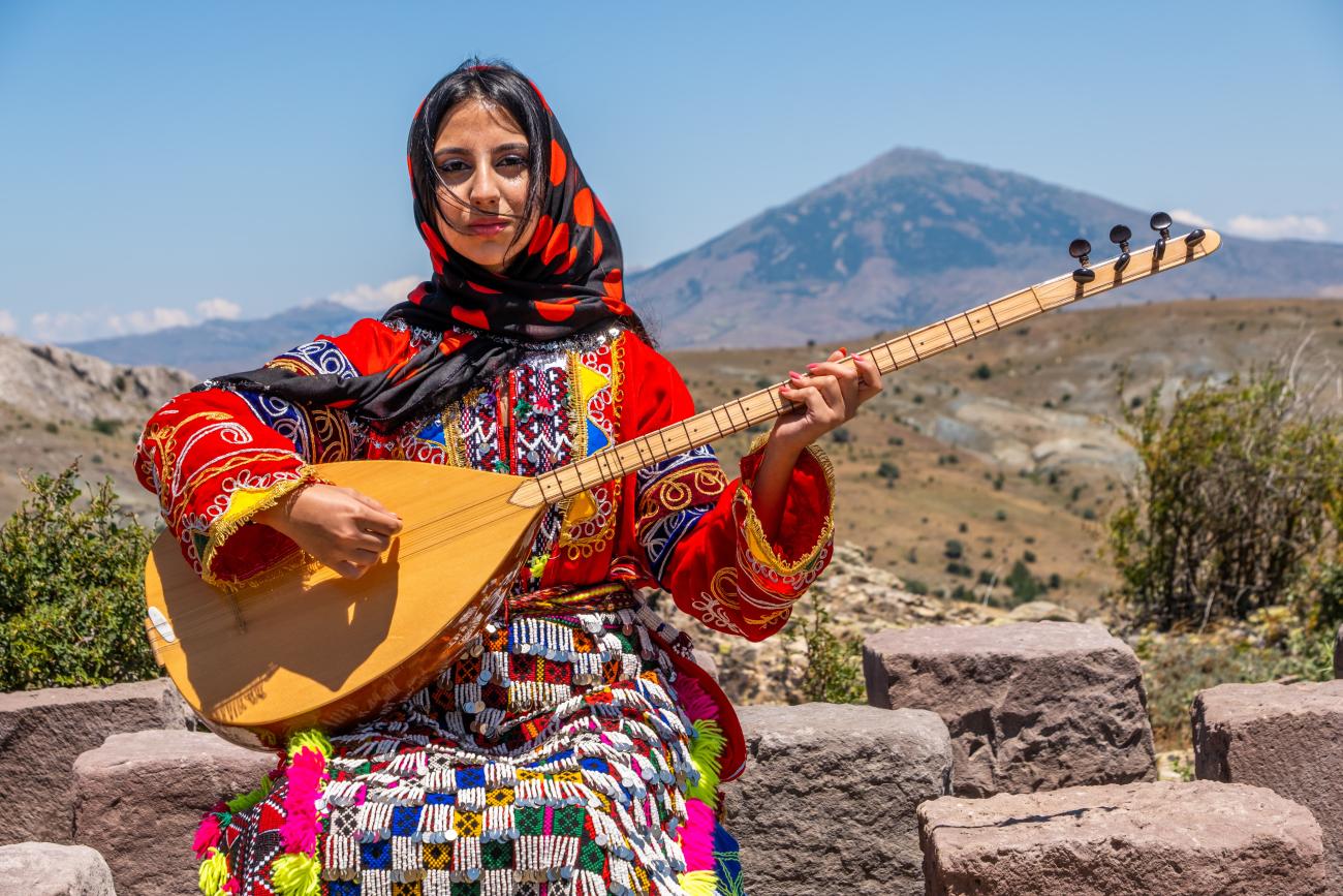Alevi woman in traditional clothing with a guitar-like instrument called Saz
